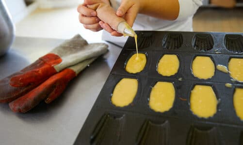 Chef patissier versant la pâte à madeleine dans des moules